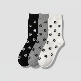 Three pairs of socks with paw prints in black, gray, and white on a woven surface.