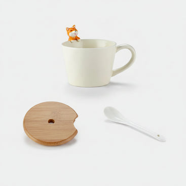 White mug with a small fox figure, wooden coaster, and white spoon on a white background