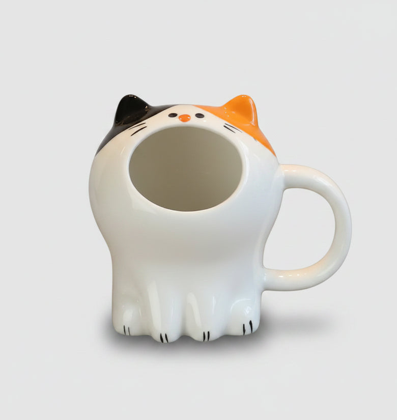 Cat-shaped mug on a wooden table with pastries in the background