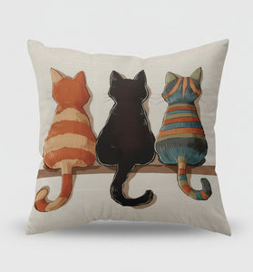 Decorative pillow with three cats on a shelf in a living room setting.