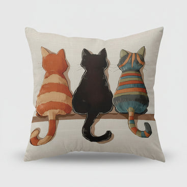 Decorative pillow with three cats on a shelf in a living room setting.