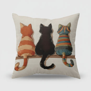 Decorative pillow with three cats on a shelf in a living room setting.