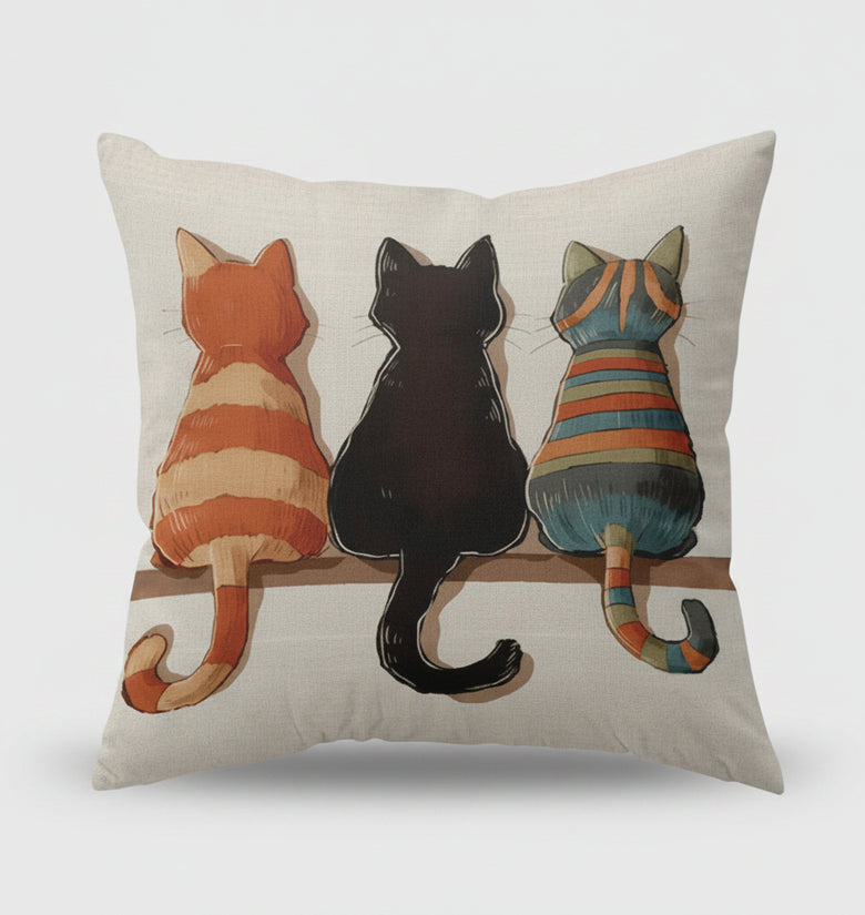 Decorative pillow with three cats on a shelf in a living room setting.