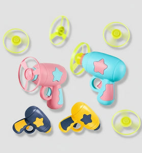 A set of colorful toy toy blasters and propeller attachments on a light gray background. The set includes three main blasters in pink, light blue, and yellow, each decorated with star-shaped cutouts, along with four separate propeller parts in neon yellow-green.