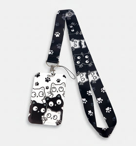 A black and white cat-themed lanyard with a matching ID badge holder. The fabric strap and badge are decorated with cartoon cat faces, paw prints, and spider webs in black and white.