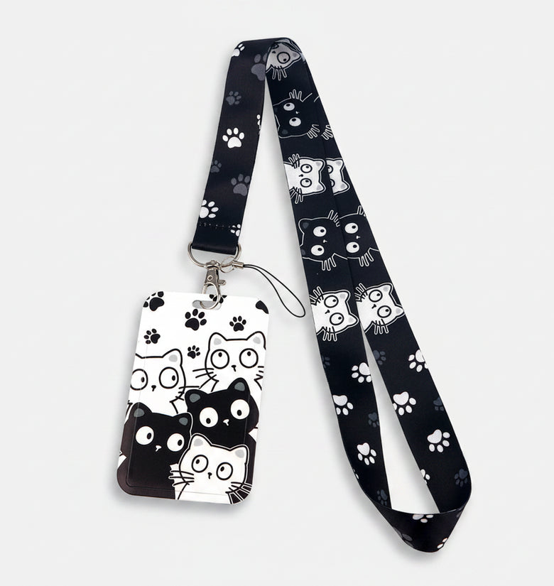 A black and white cat-themed lanyard with a matching ID badge holder. The fabric strap and badge are decorated with cartoon cat faces, paw prints, and spider webs in black and white.