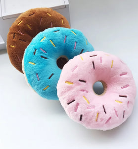 Three colorful donut-shaped plush toys on a white surface