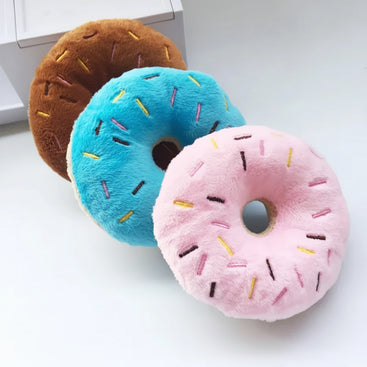 Three colorful donut-shaped plush toys on a white surface