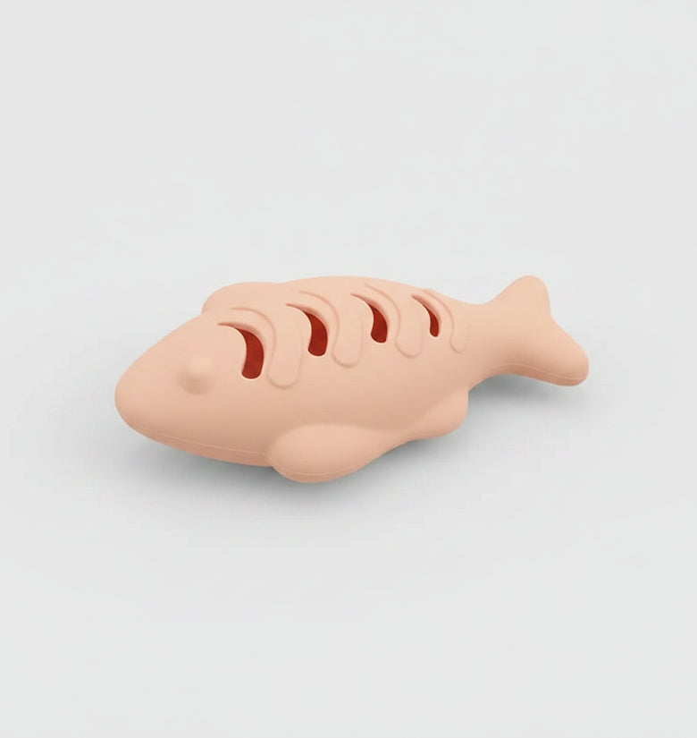 Cat playing with a silicone toy shaped like a fish, with text on both sides.