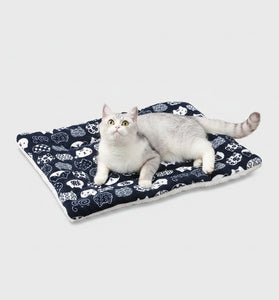 Cat lying on a patterned mat on a wooden floor