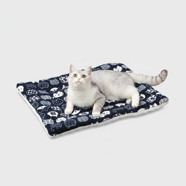 Cat lying on a patterned mat on a wooden floor