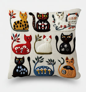 Decorative pillow with embroidered cats in various colors on a white background