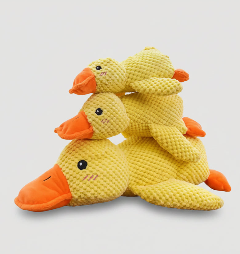 Three stacked yellow plush duck toys with orange beaks and black eyes, photographed on a light gray background.